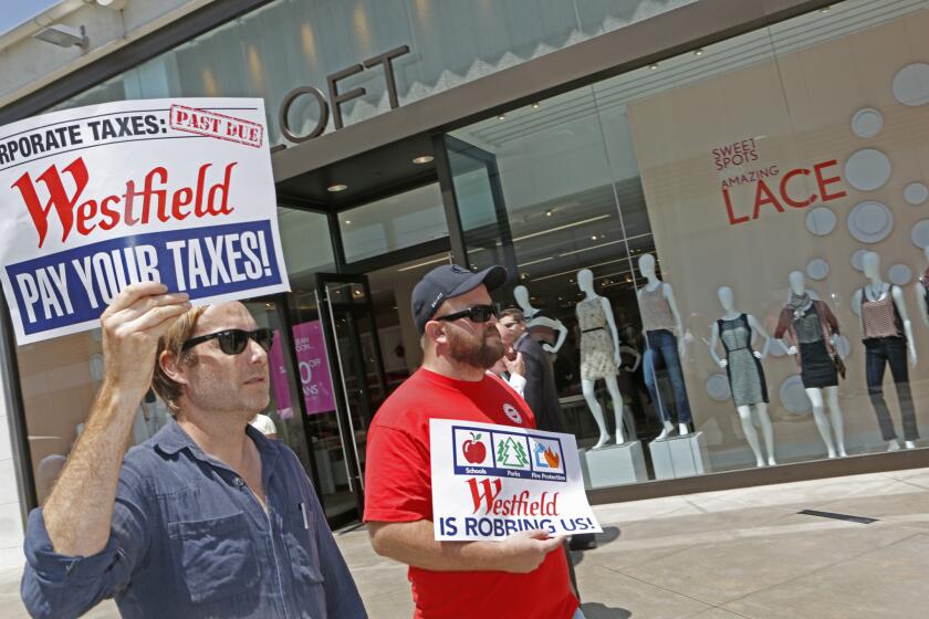 Nate Greely, left, and James Banks of Refund LA carry signs in a protest against Westfield Century City Mall on July 31, 2013.