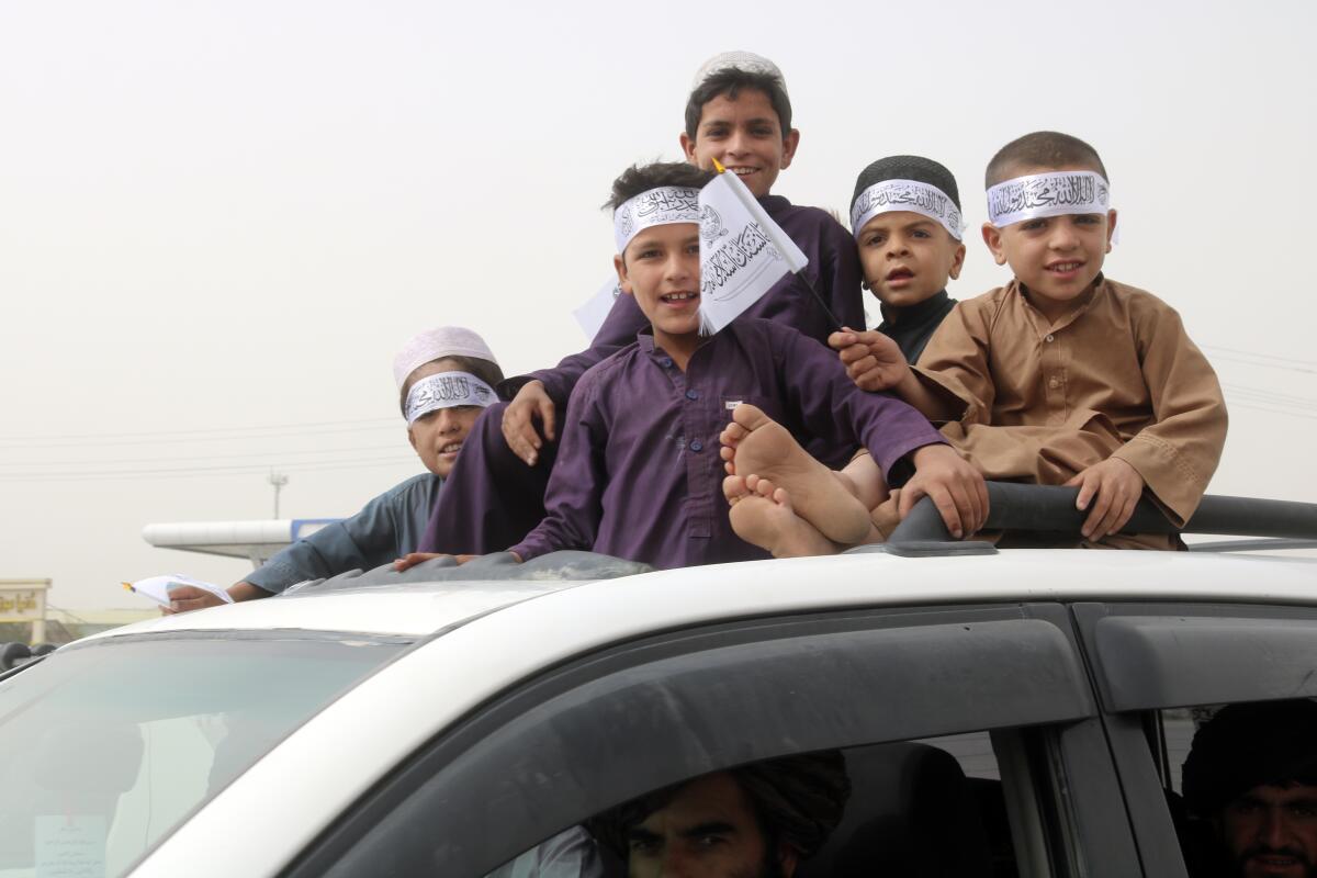 Niños alzan banderas del Talibán en un festejo del 2do aniversario 