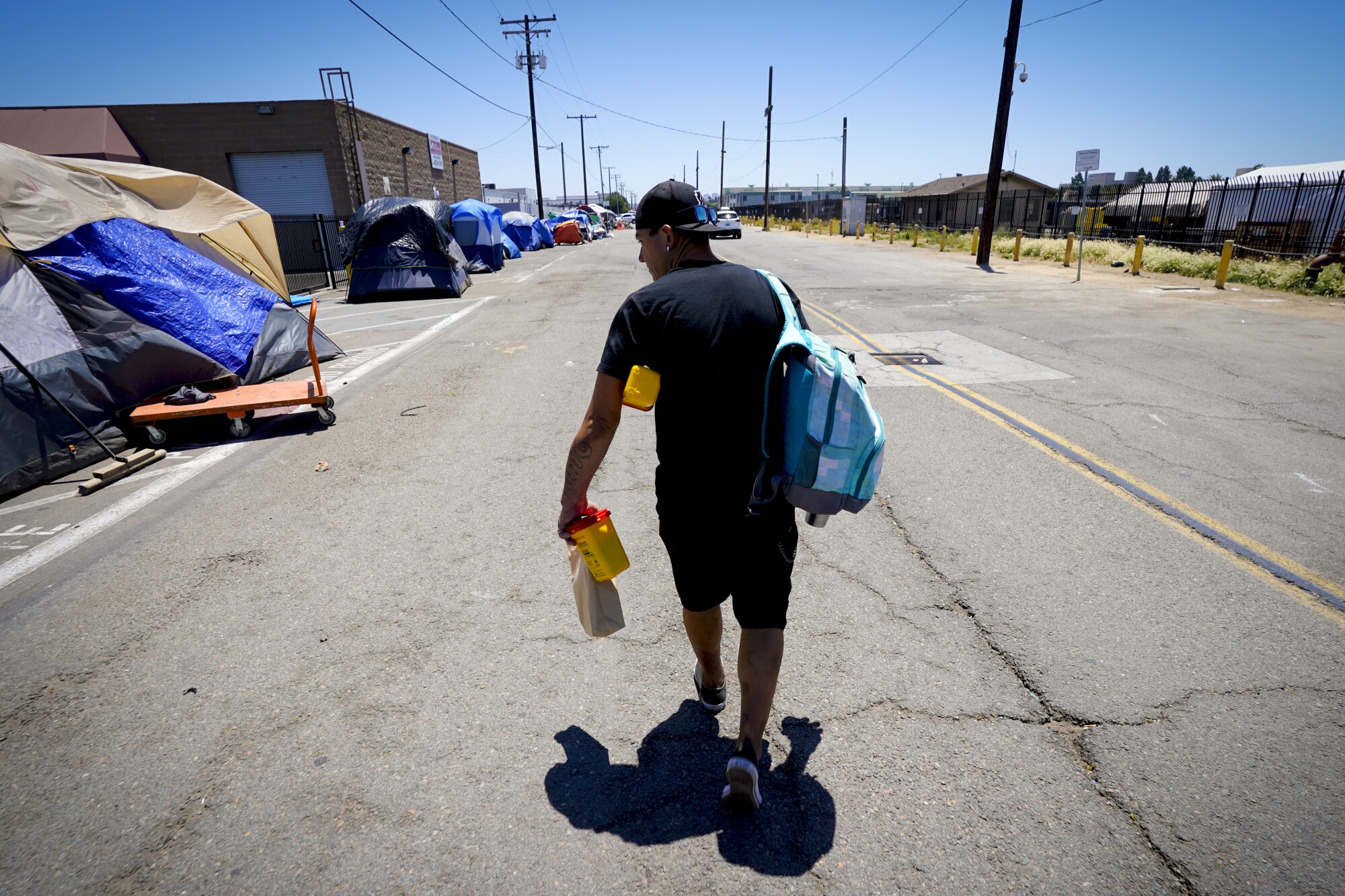 Billy walks past several tents at a homeless encampment
