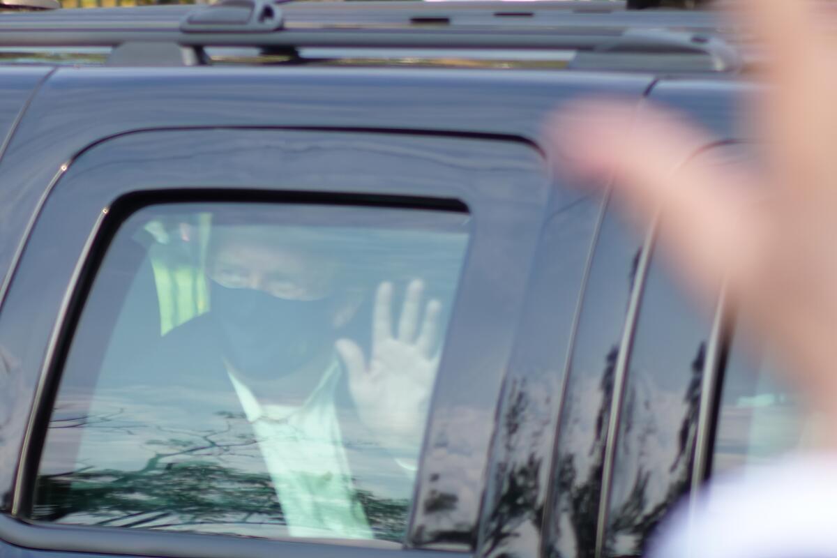El presidente Donald Trump saluda a simpatizantes desde un vehículo afuera del Centro Médico Militar