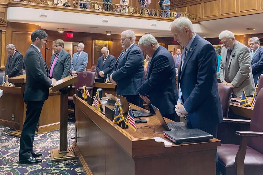 Indiana House lawmakers bow their heads Thursday, Aug. 4, 2022, in Indianapolis, while Republican Rep. Timothy Wesco, left, honors GOP U.S. Rep. Jackie Walorski, who died Wednesday, Aug. 3, in a car crash in her northern Indiana district. Wesco now represents the district Walorski served during her six years in the state's Legislature. (AP Photo/Arleigh Rodgers)