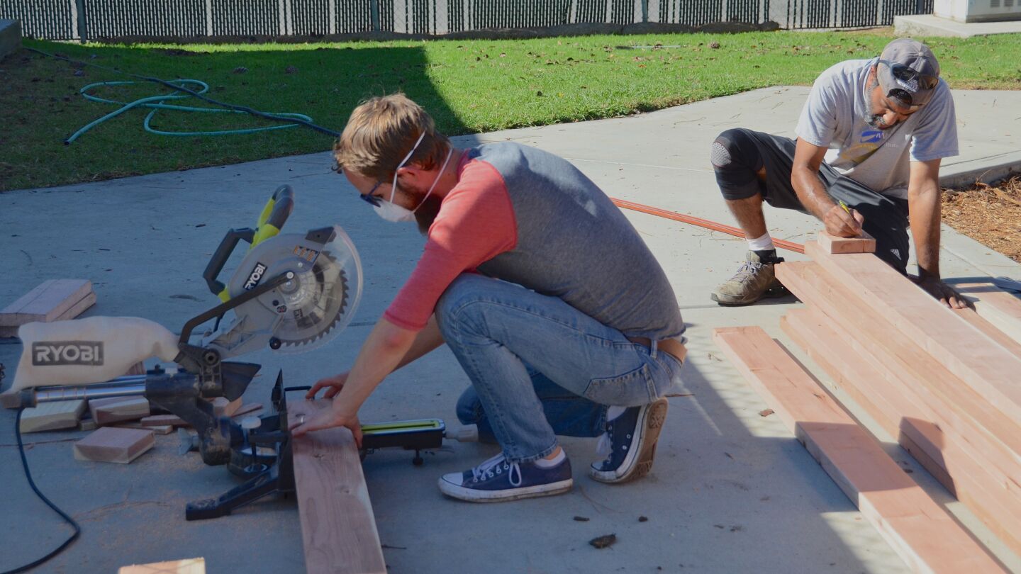 Parent volunteers Mark Hendrickson, left, and Ashvind Singh measure and cut wood for planter boxes at Sycamore Creek Community Charter School in Huntington Beach.