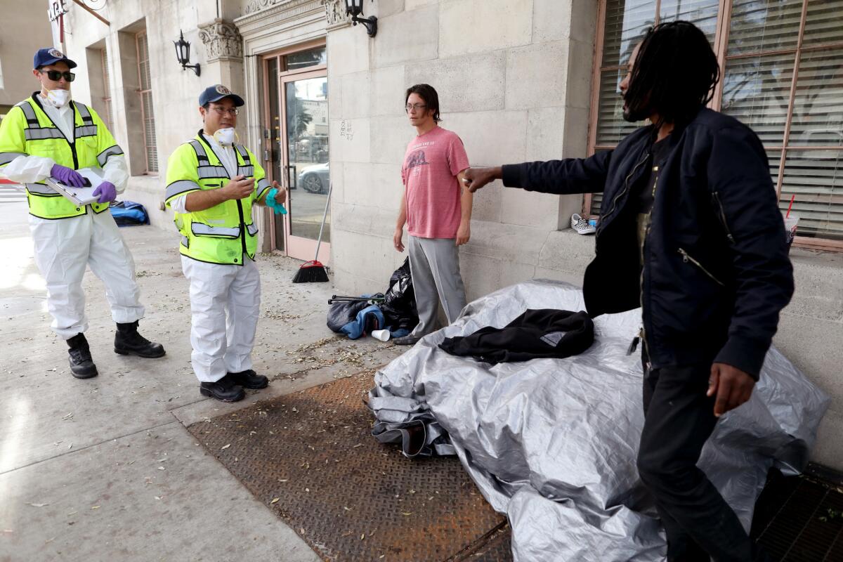 L.A. sanitation workers tell homeless people where to put their belonging to be in compliance with the law. Since a shelter opened in Hollywood this month, the city has stepped up enforcement at nearby encampments.