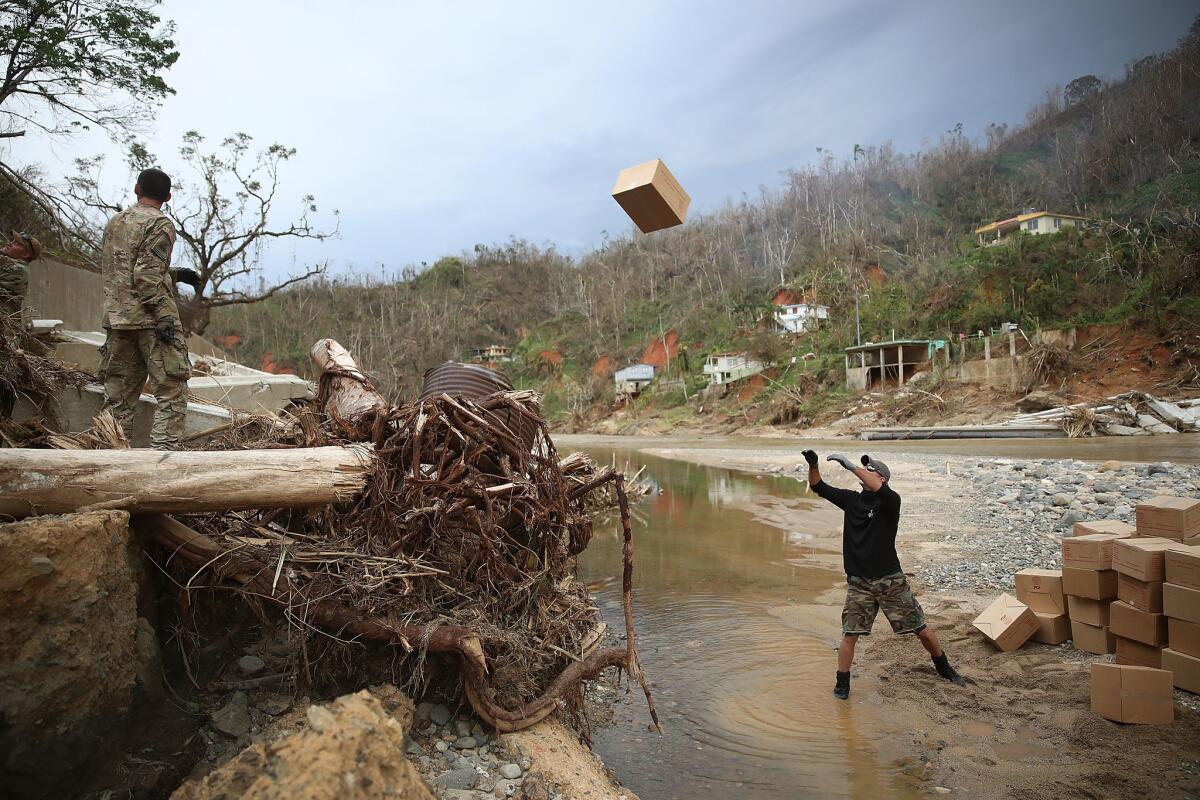 Daniel Braithwaite, right, prepares to catch a box of ready-to-eat meals delivered by U.S. Army 1st Special Forces Command soldiers to Utuado, Puerto Rico.