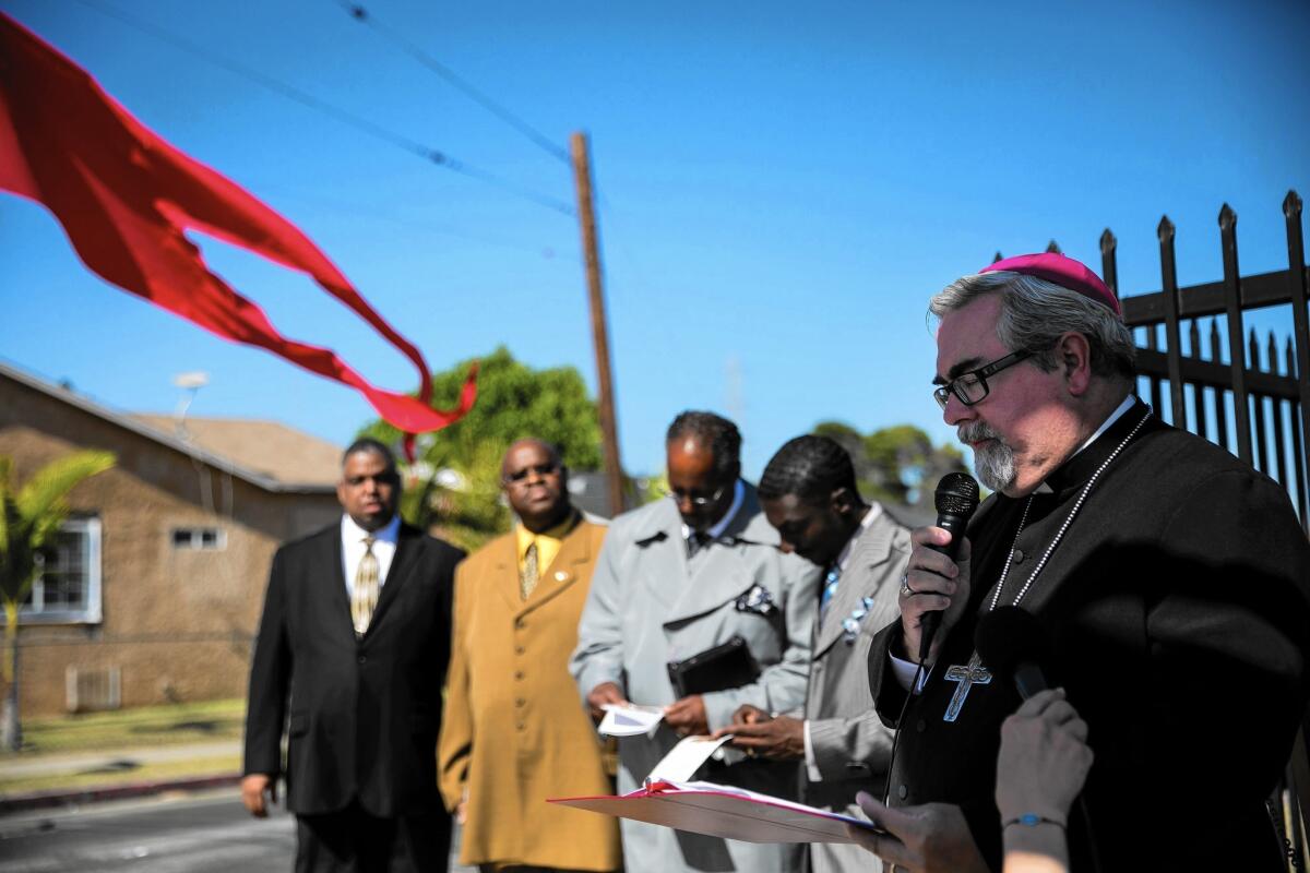 Bishop Guy Erwin of the Evangelical Lutheran Church in America, far right, says a prayer at an interfaith service marking the 50th anniversary of the Watts riots on Sunday.