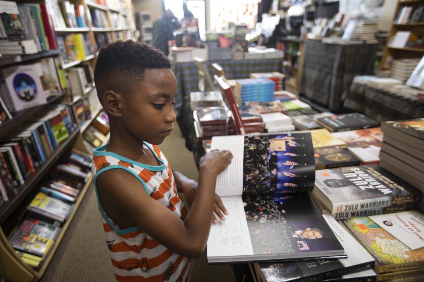 Jace Hankerson-Mayo, 7, looks at a photo of President Obama in a book at Eso Won Books.