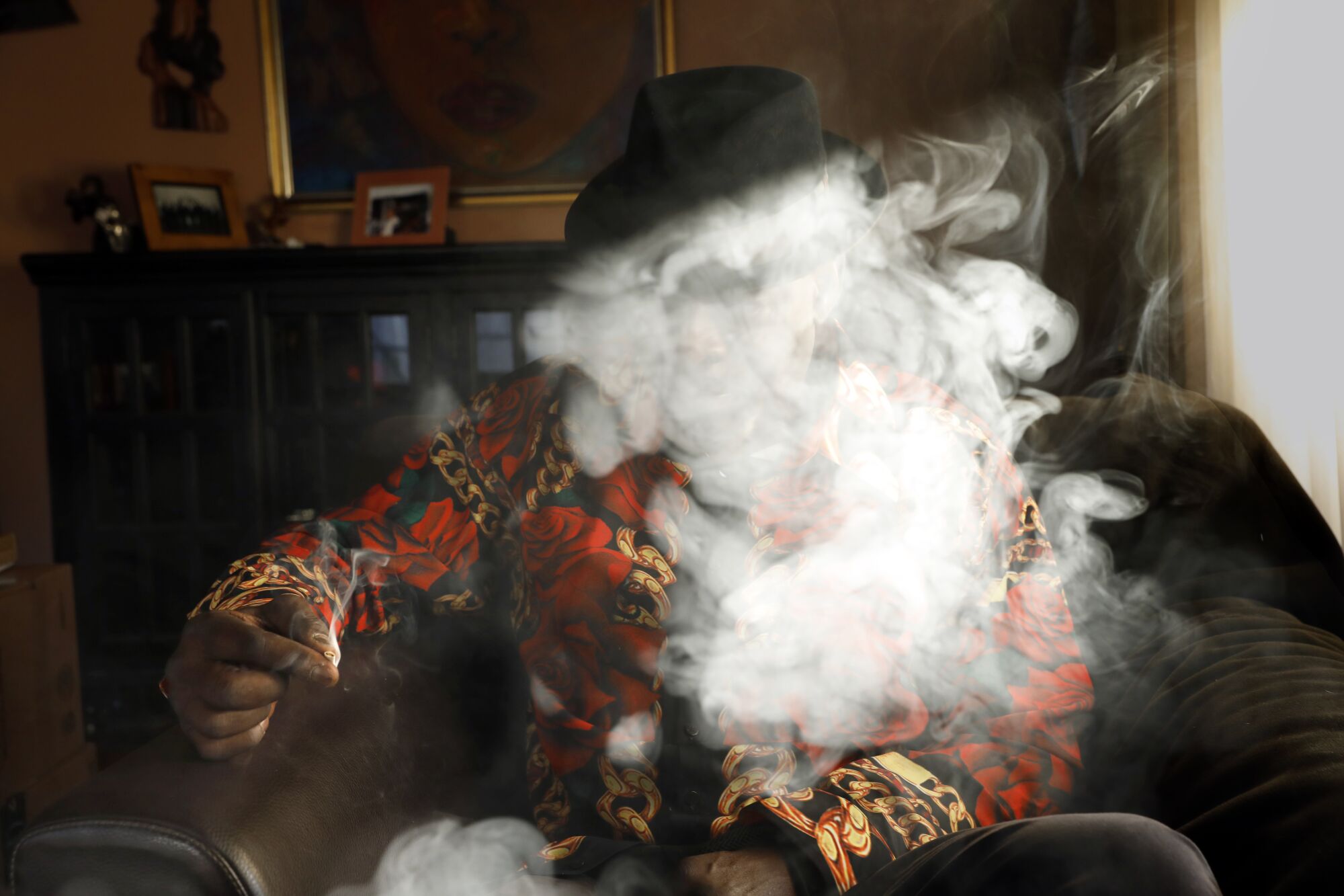 A man sits behind a cloud of smoke in a room