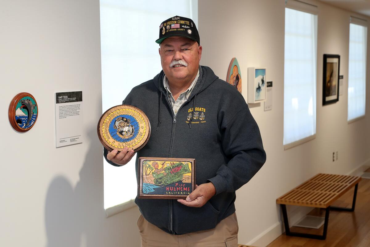 U.S. Navy veteran Gary Tegel, 59, of Costa Mesa, poses with his wood-burnt art at the new art exhibit "Through Their Eyes."
