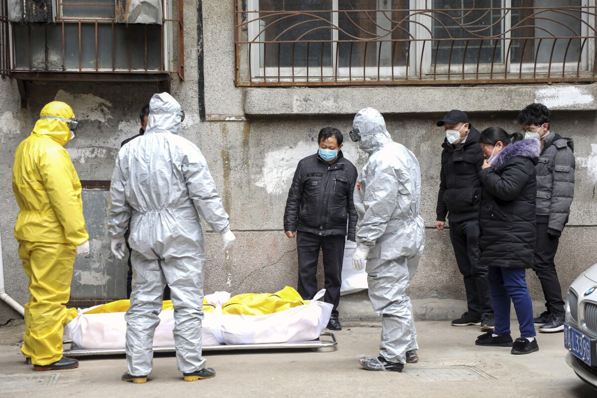 Workers stand around a body wrapped plastic