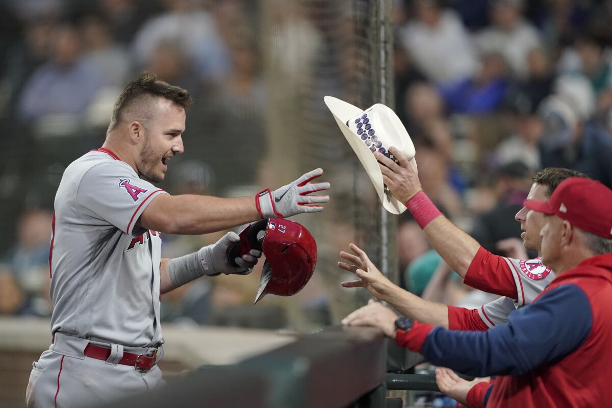 Angels' Mike Trout reaches for a cowboy hat at the dugout after he hit a two-run home run against the Seattle Mariners.