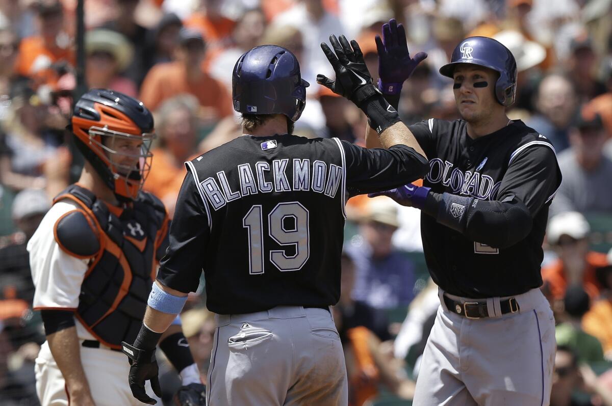 Colorado's Troy Tulowitzki, right, celebrates with his teammate Charlie Blackmon (19) in front of San Francisco's Buster Posey after hitting a two-run home run in the third inning of a Rockies victory over the Giants, 8-7.