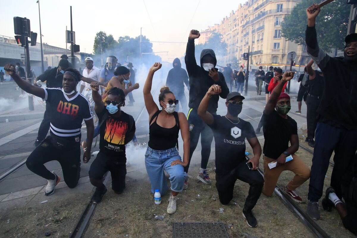 French demonstrators kneel and raise fists in a street protest.