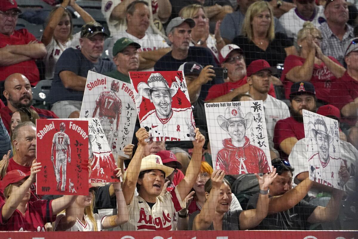 Fans hold up pictures of Angels star Shohei Ohtani and his interpreter, Ippei Mizuhara during the game.