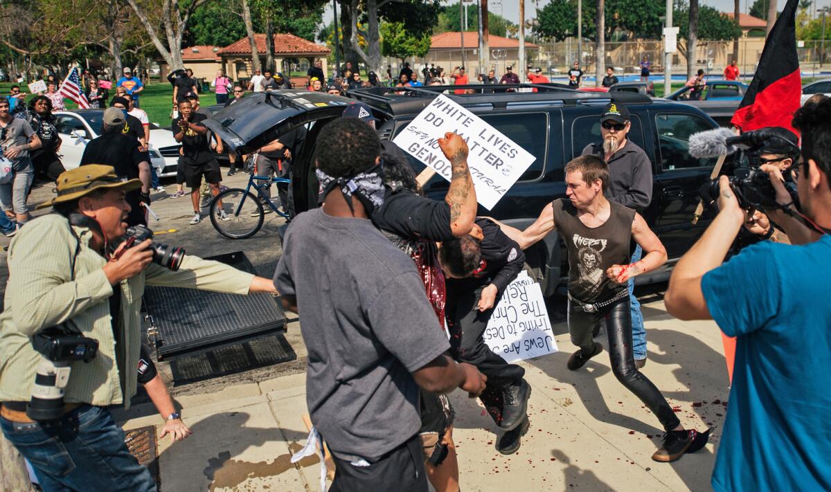 This photo provided by the OC Weekly shows a KKK member stabbing a protester as members of the white supremacy group prepare to rally against immigration at Pearson Park in Anaheim on Saturday.