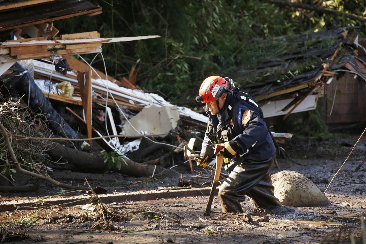 An Orange County search and rescue team member slogs through the mud along Olive Mill Road at Hot Springs Road in Montecito.