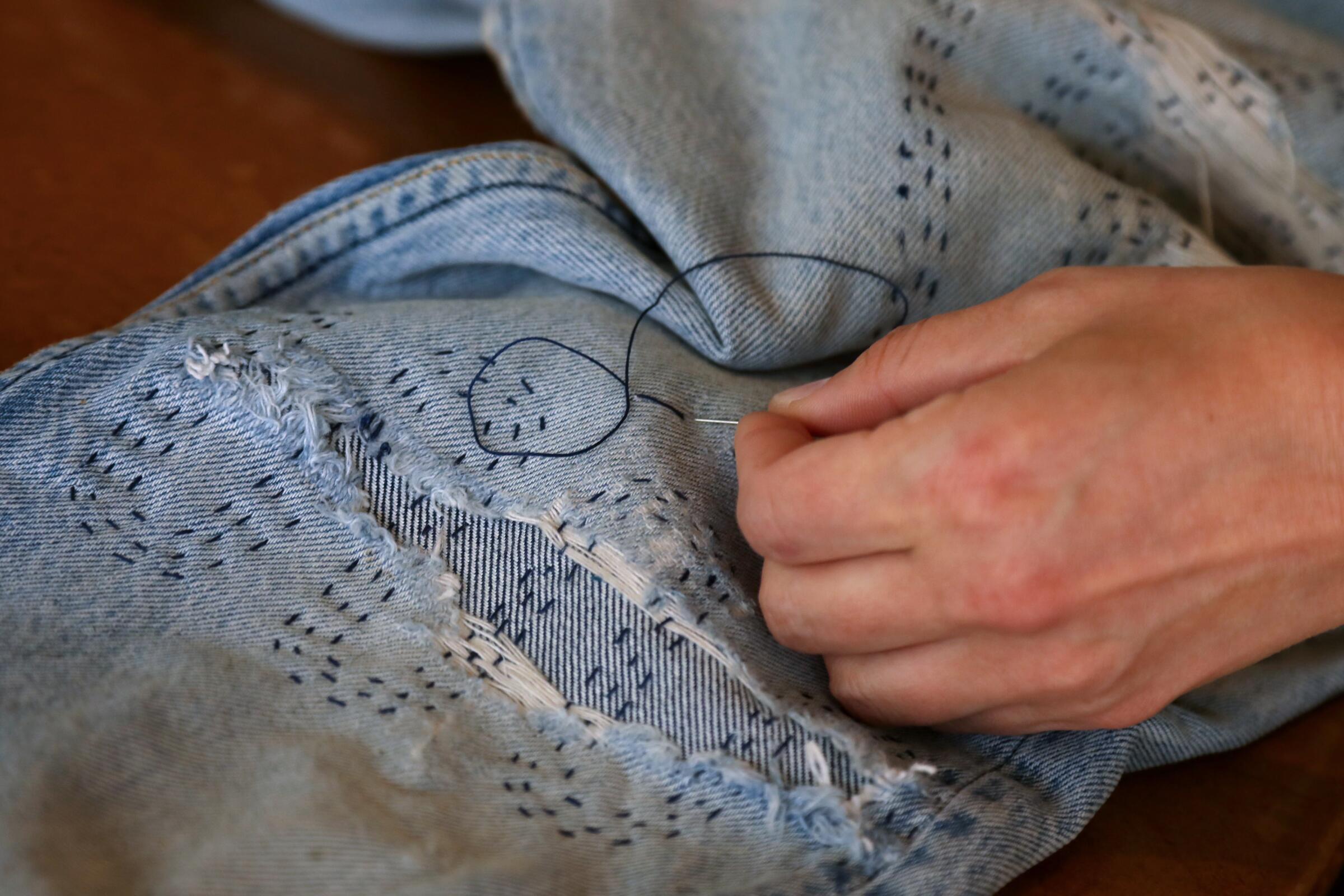 Weathered jeans are hand-stitched.