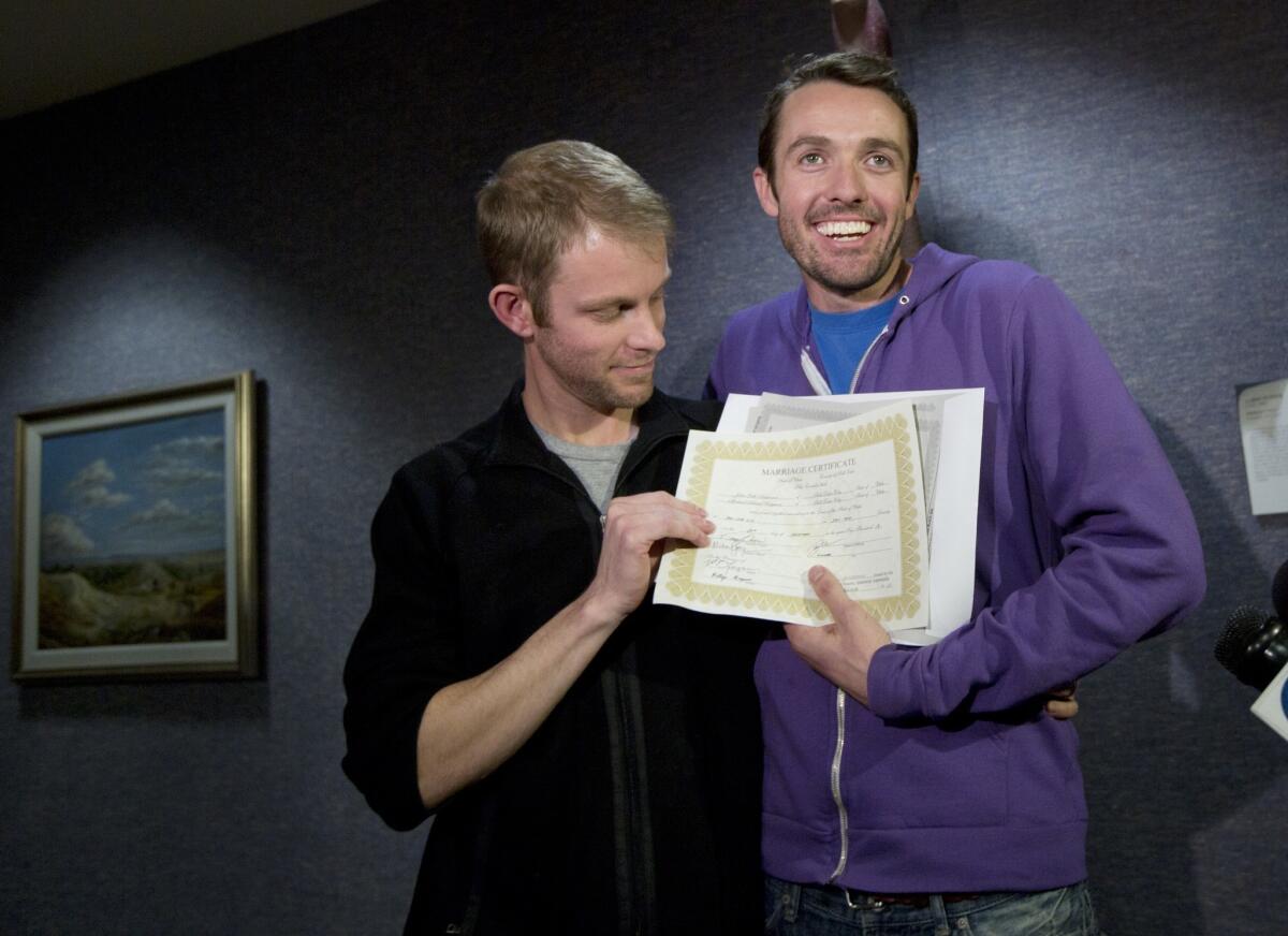Seth Anderson, left, and Michael Ferguson hold up their marriage certificate and license outside the Salt Lake County Clerk's Office in Salt Lake City on Friday, the day a judge struck down Utah's ban on same-sex marriage.