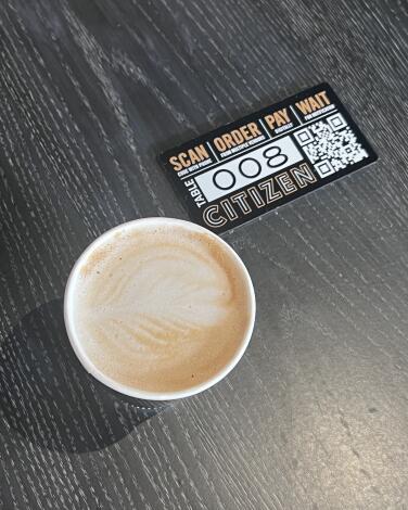 Overhead photo of a pumpkin spice latte next to a table QR code