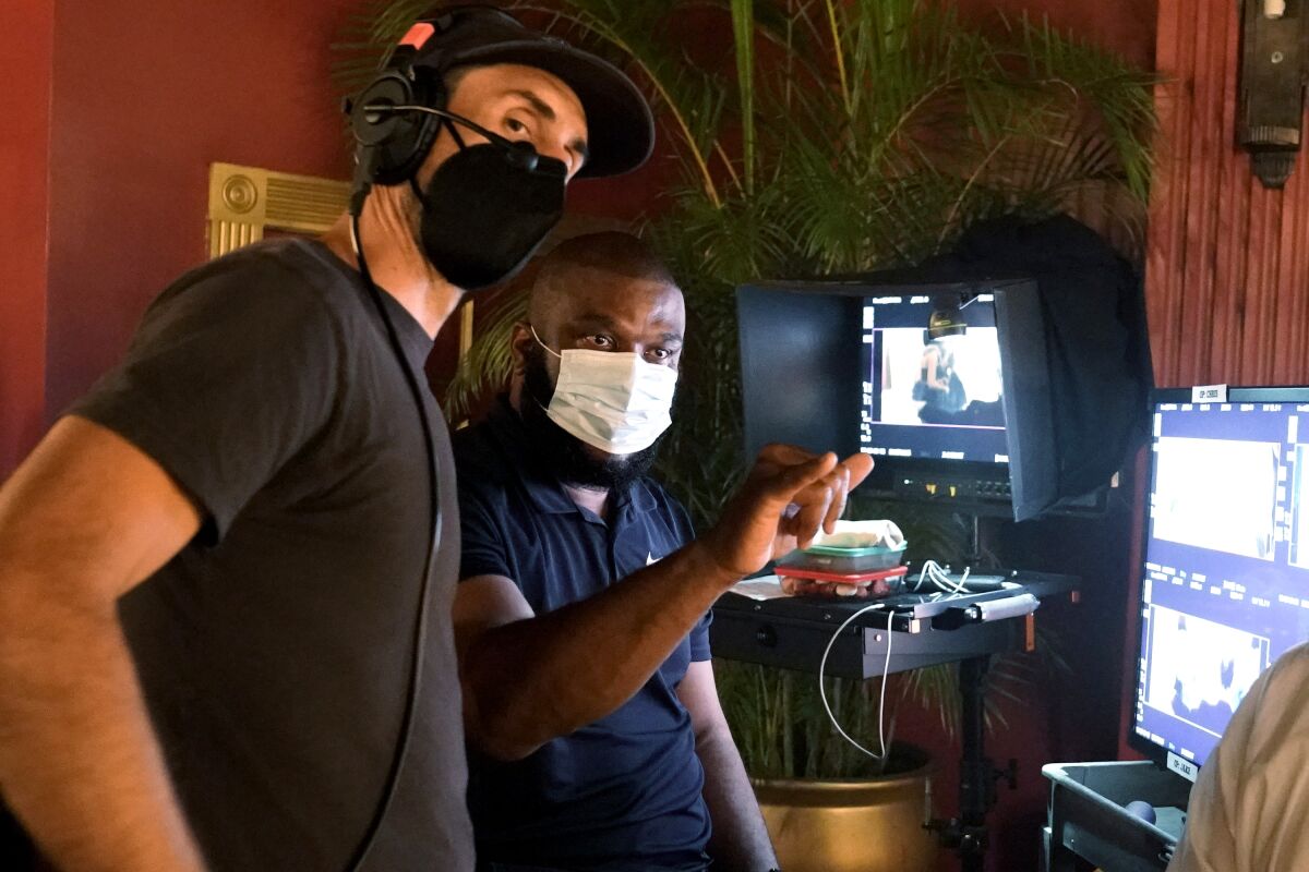 Two men wearing face masks confer on a movie set. 