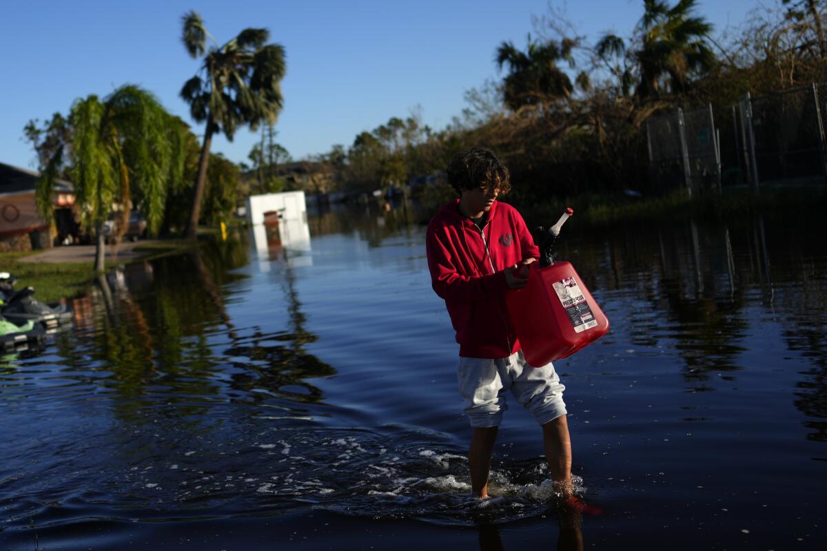 A teenager carrying a fuel can as he walks through floodwater.