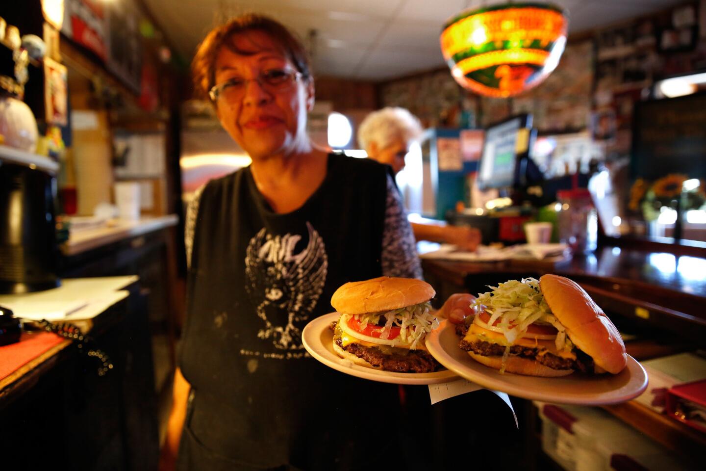 Waitress Patricia Moya delivers hot green chile cheeseburgers at the Owl Bar and Cafe in San Antonio, N.M.