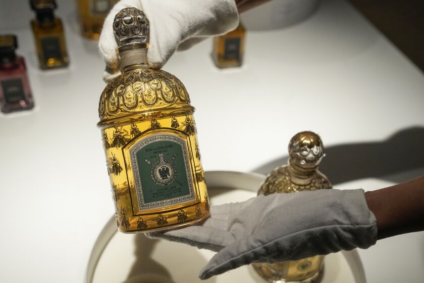 Guerlain's Director of Art, Culture and Heritage Ann-Caroline Prazan displays an Eau de Cologne Imperial Bee bottle imagine by Pierre-Francois Guerlain at the archive in Paris, Tuesday, May 30, 2023. Guerlain, the house which invented modern perfumery, has created its first ever archive — and with it has unveiled the unimaginable inventions and fabulous stories that have marked the French company’s sensational past. (AP Photo/Michel Euler)