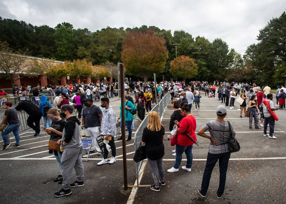 Hundreds of people wait in line for early voting on Monday, Oct. 12, 2020, in Marietta, Georgia. Eager voters have waited six hours or more in the former Republican stronghold of Cobb County, and lines have wrapped around buildings in solidly Democratic DeKalb County. (AP Photo/Ron Harris)