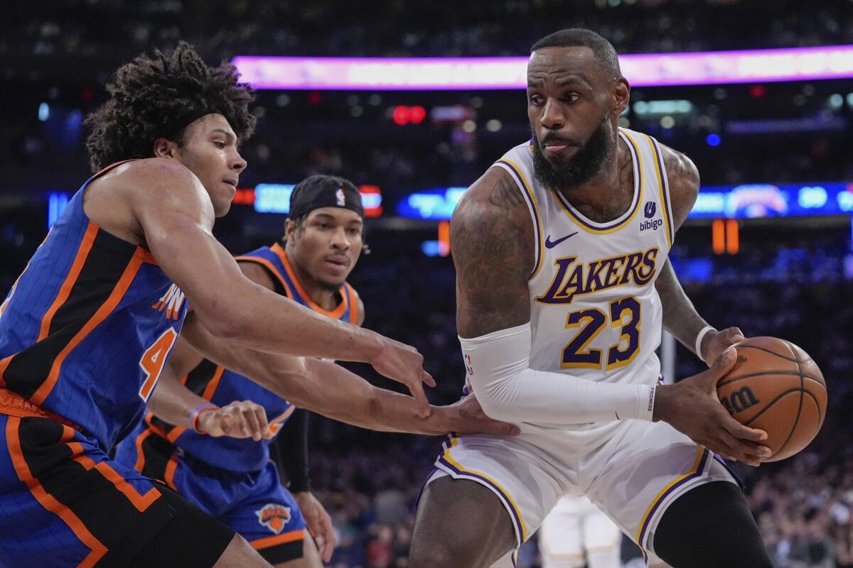 Lakers star LeBron James, right, controls the ball in front of New York Knicks center Jericho Sims.