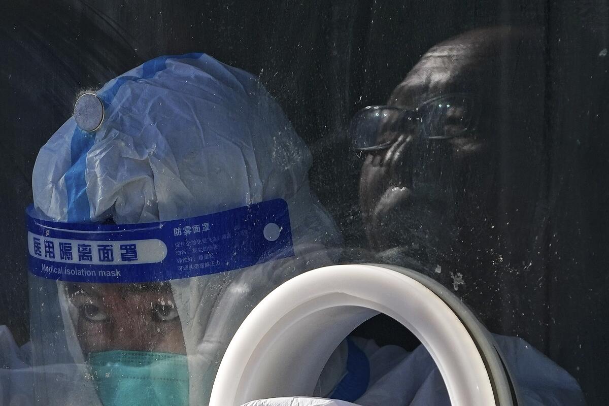 A medical worker wearing protective gear collects a sample from a man at a coronavirus test site in Beijing.