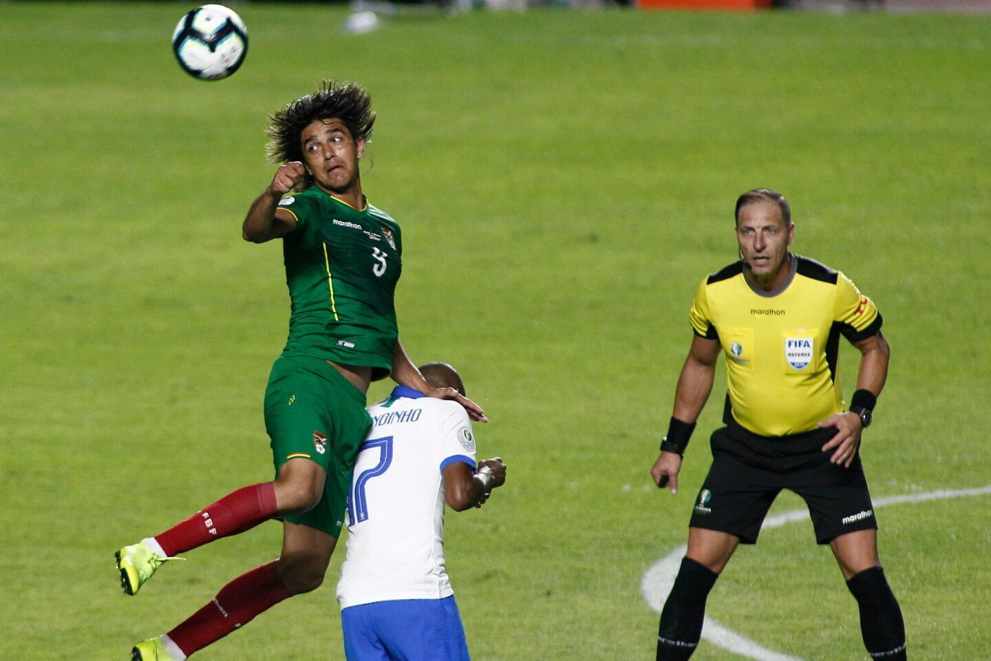 Bolivia's Marcelo Martins (L) jumps over Brazil's Fernandinho as Argentine referee Nestor Pitana looks on during their Copa America football tournament group match at the Cicero Pompeu de Toledo Stadium, also known as Morumbi, in Sao Paulo, Brazil, on June 14, 2019.
