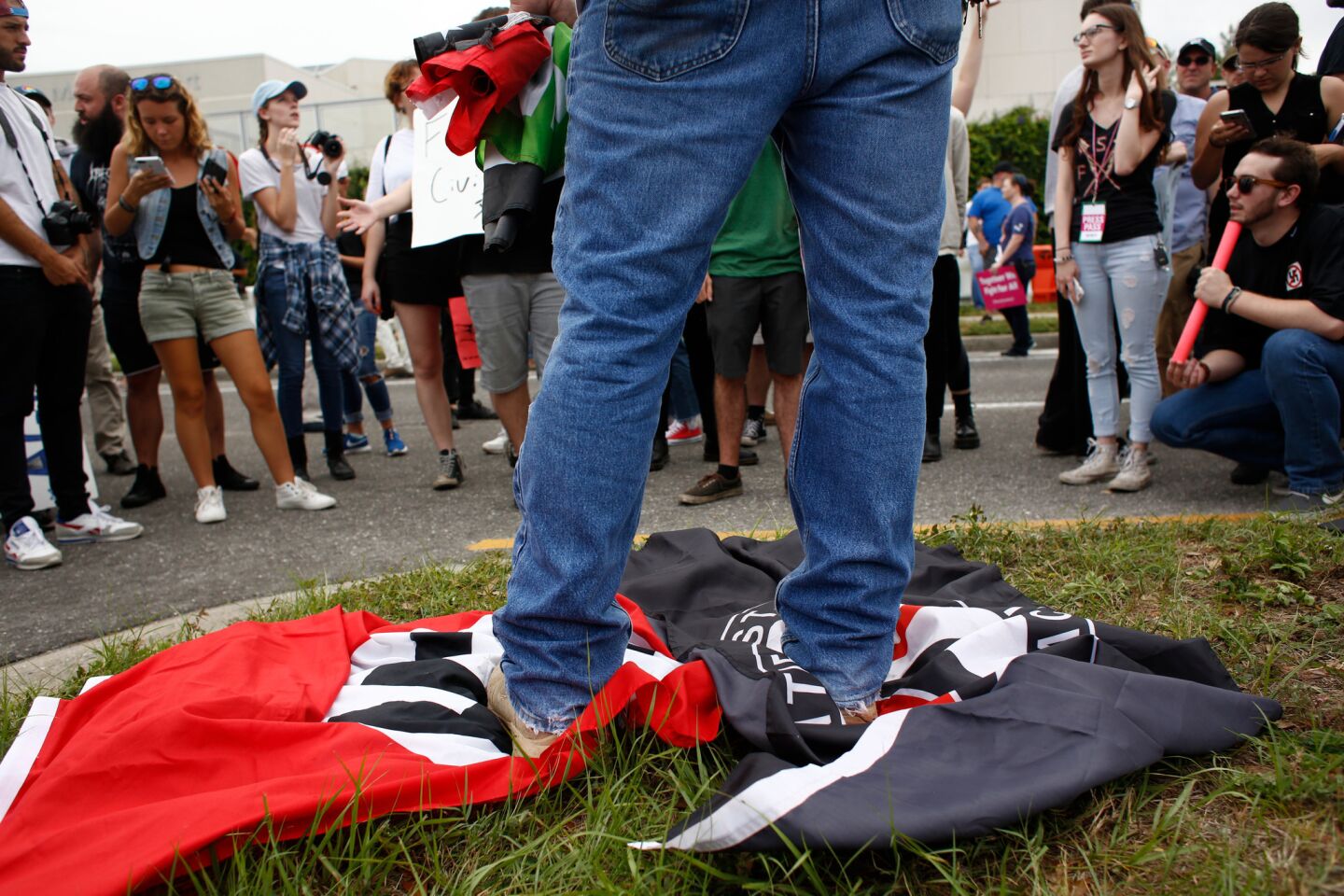 A man stands on a Nazi flag and an Antifa flag near the site of a planned speech by white nationalist Richard Spencer at the University of Florida campus in Gainesville.