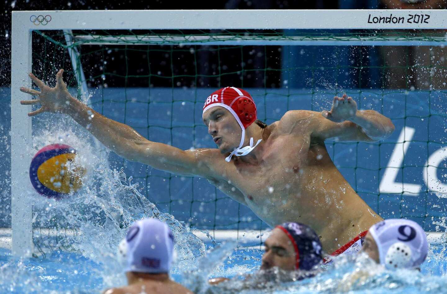 Ed Scott of Great Britain is unable to stop a shot by Anthony Azevedo of the United States during a preliminary men's water polo match.