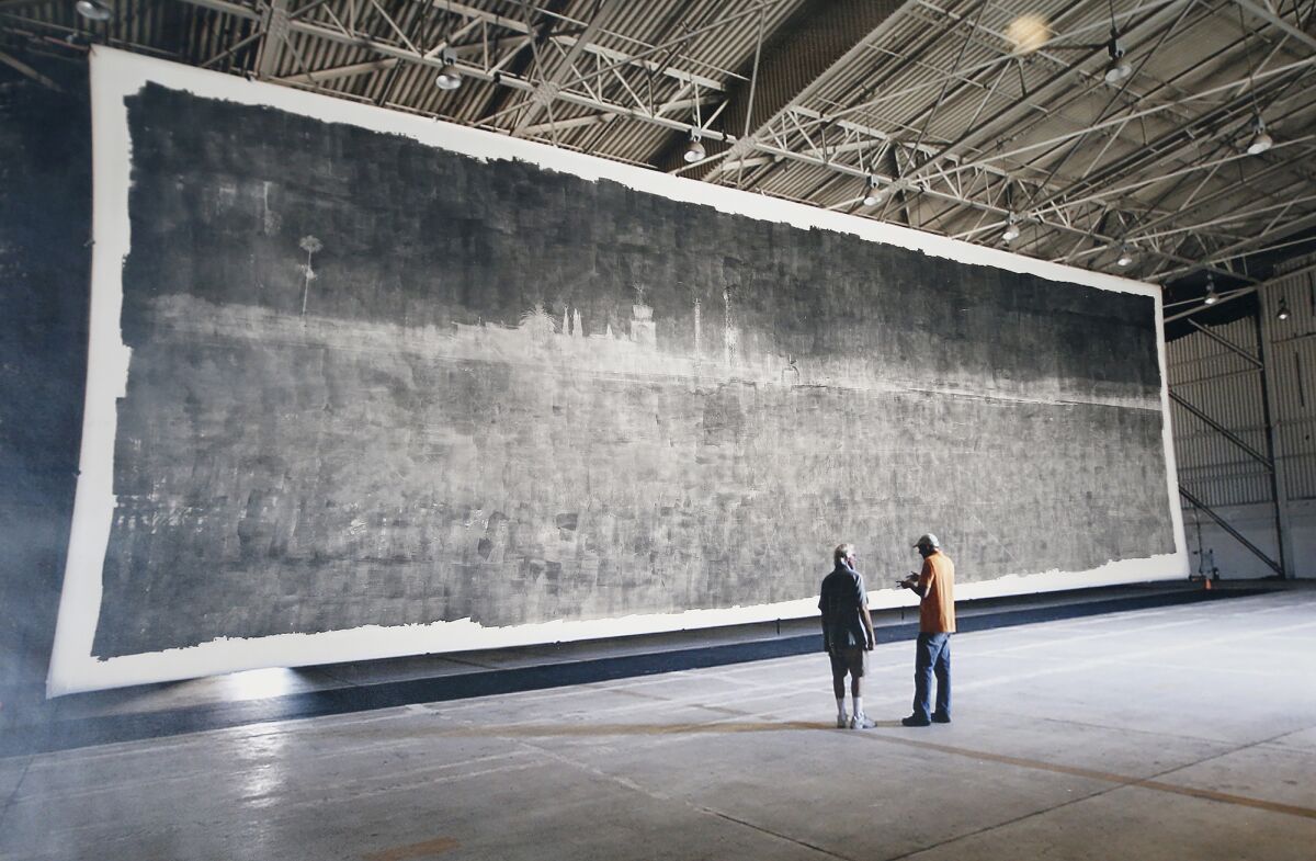 Two people stand in front of a giant photo.