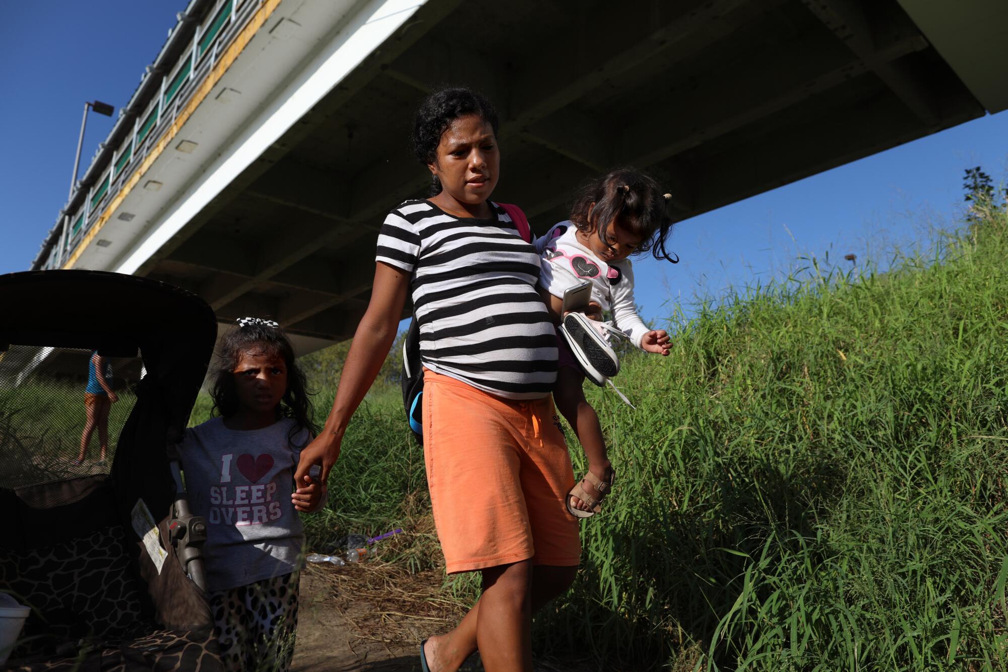 A woman with two young girls under a bridge.