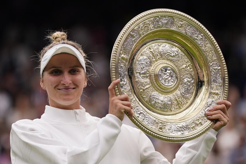 The Czech Republic's Marketa Vondrousova holds up the Wimbledon trophy and smiles 