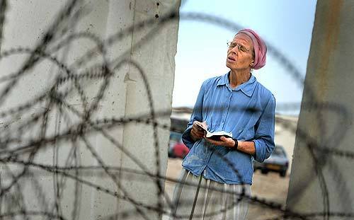 A settler prays behind barbed wire and concrete separating the enclave of Shirat HaYam and Palestinian land. Many of the religious as well as secular Jews are praying for a miracle from God to save their way of life.