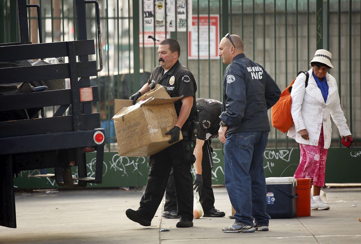 Officers remove a homeless person's belongings last week in downtown Los Angeles' skid row. On Wednesday, the L.A. City Council approved a measure limiting how much property homeless people can keep with them on the streets.
