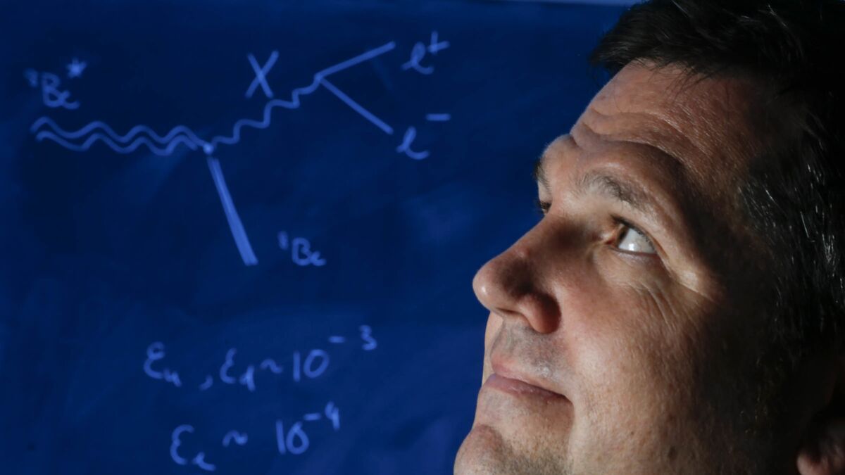 Tim Tait, Ph.d., a theoretical physicist at UC Irvine stands next to a chalkboard with calculations that show a few of the details of a study that he co-authored about a tiny, unseen force could potentially alter our basic understanding of the universe.