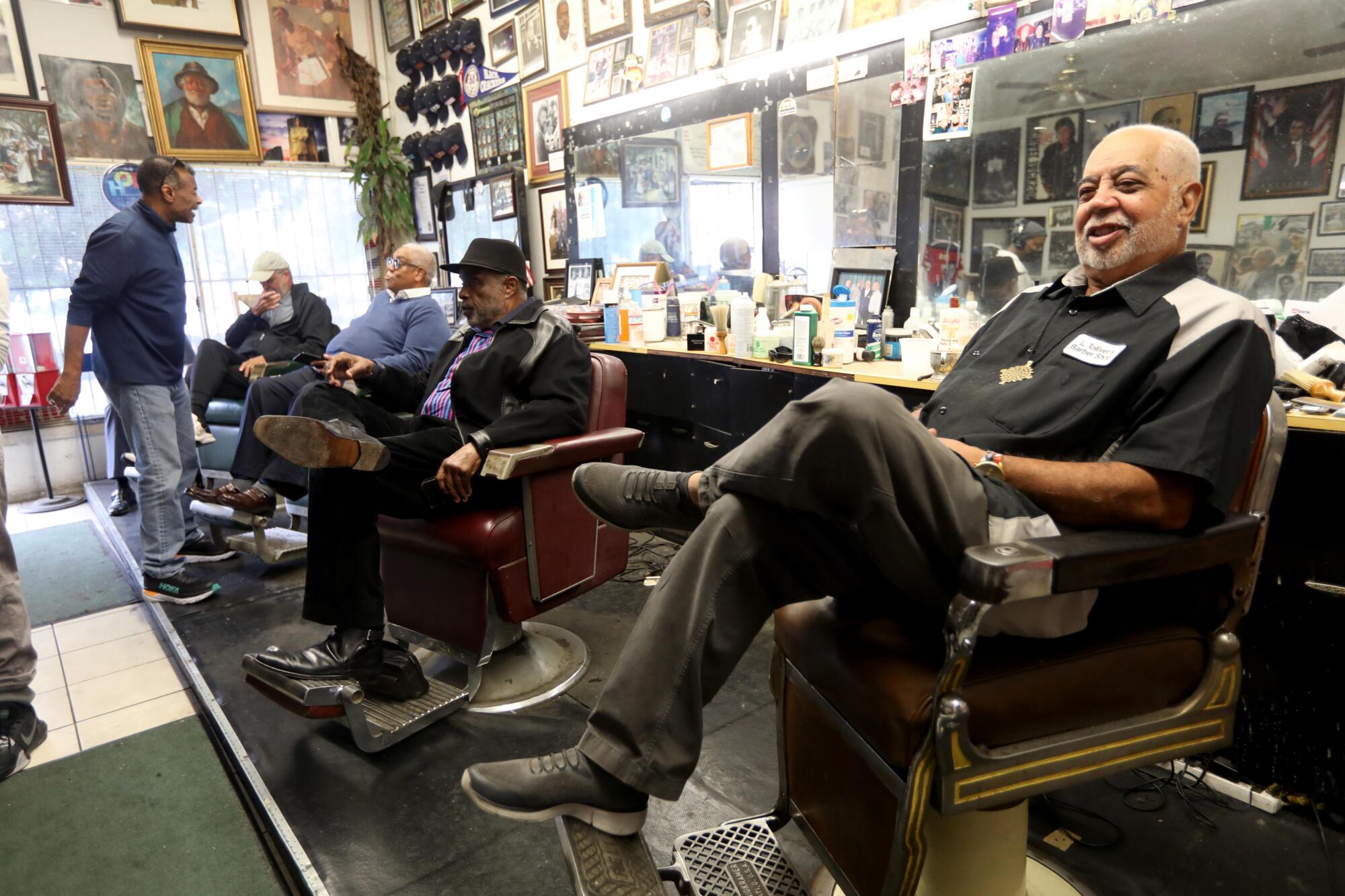 Lawrence Tolliver waits for customers while others converse about issues of the day at Tolliver's Barbershop.