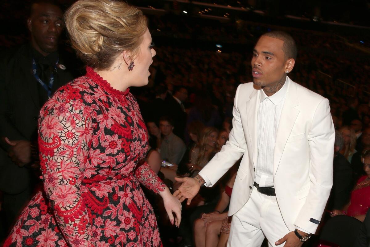 "Set Fire to the Rain" singer Adele, left, pictured here with Chris Brown, was spotted with an "A" script tattoo on her neck that has people believing that might be the first initial of her new son's name.
