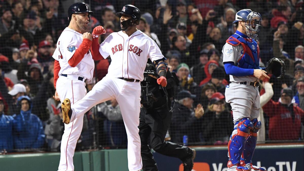 Red Sox's Eduardo Nunez celebrates with teammate J.D. Martinez after hitting a three-run home run as Dodgers' Yasmandi Grandal waits in the seventh inning of Game 1 of the World Series at Fenway Park on Tuesday in Boston.