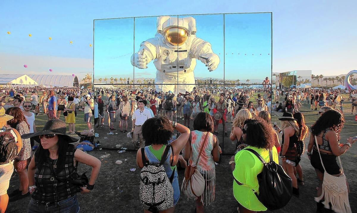 A nearly 40-foot-tall astronaut "Escape Velocity" by Poetic Kinetics, an L.A.-based art collective, is reflected in "Reflection Fields" by Phillip K. Smith as it roams through the crowd at the Coachella Valley Music and Arts Festival April 11, 2014, in Indio.