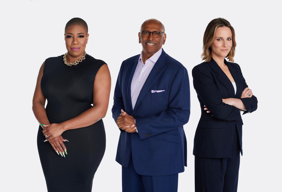 Three broadcast journalists stand together professionally while clad in a black dress, a blue suit and a black suit