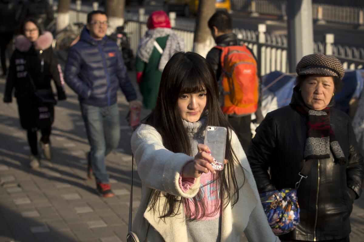 2016年2月28日，北京，18岁的网络表演者王伟英（音）在街上走路时用智能手机直播。