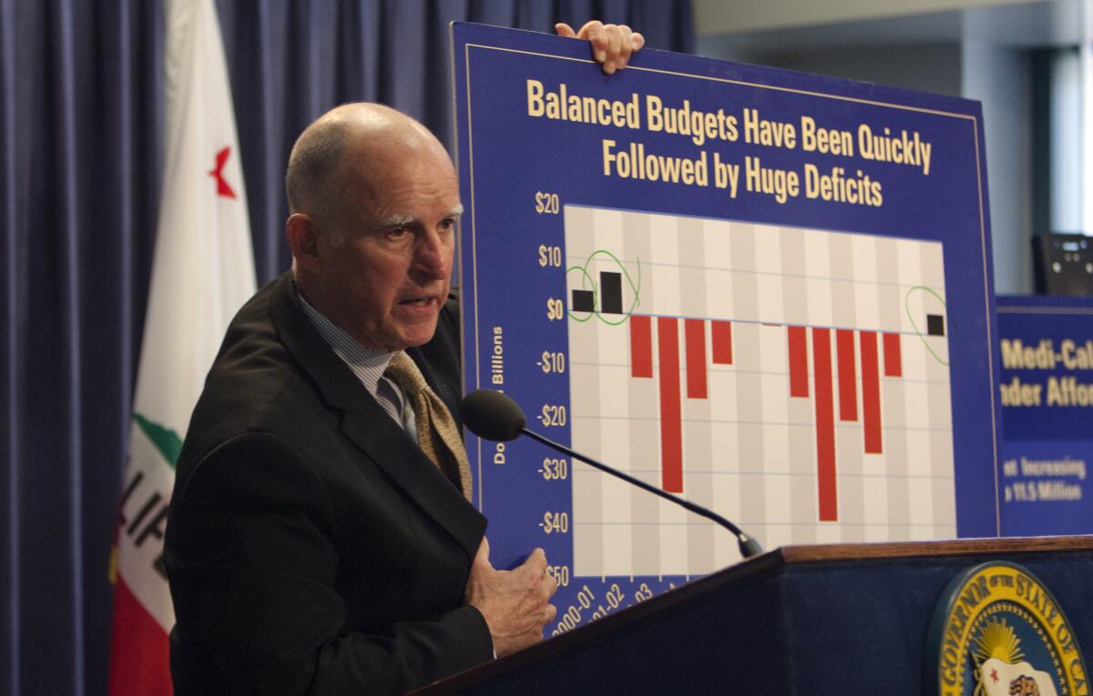 Gov. Jerry Brown holds a poster showing the history of California budget deficits while announcing his revised 2014-15 spending proposal on Tuesday.