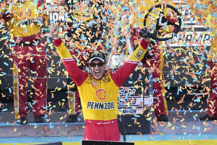 Joey Logano celebrates after winning a NASCAR Cup Series auto race and championship.