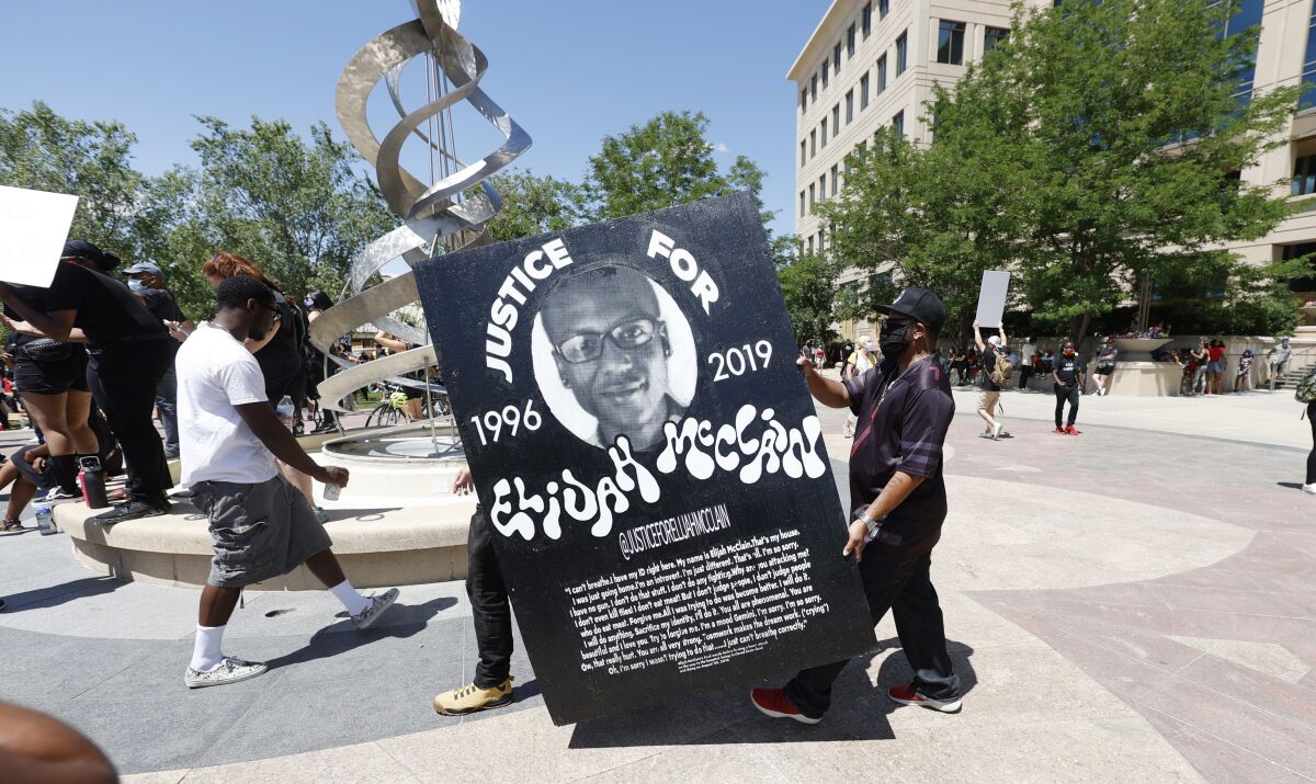 FILE - In this June 27, 2020, file photo, demonstrators carry a giant placard during a rally and march over the death of 23-year-old Elijah McClain outside the police department in Aurora, Colo. Three police officers and two paramedics indicted on manslaughter and other charges in the 2019 death of Elijah McClain appeared in court for the first time Monday, Nov. 1, 2021, since being charged.(AP Photo/David Zalubowski, File)