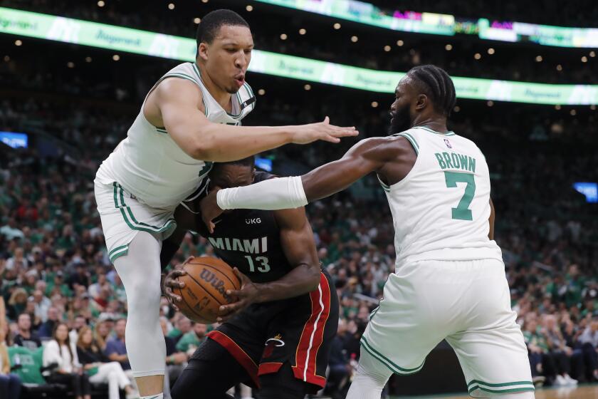 Boston Celtics' Grant Williams, left, lands on Miami Heat's Bam Adebayo (13) while trying to block a shot, next to Celtics' Jaylen Brown (7) during the first half of Game 3 of the NBA basketball playoffs Eastern Conference finals Saturday, May 21, 2022, in Boston. (AP Photo/Michael Dwyer)
