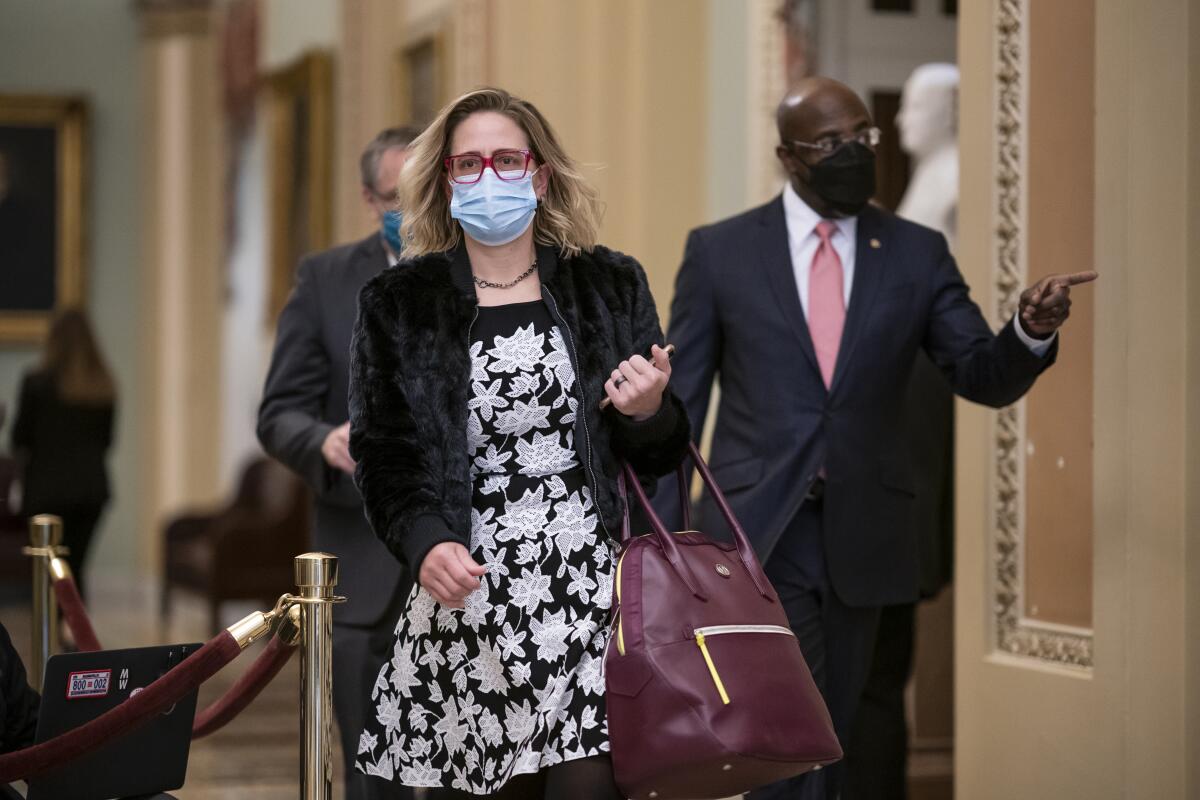 Sen. Kyrsten Sinema, masked and walking with Sen. Raphael Warnock in the Capitol. 