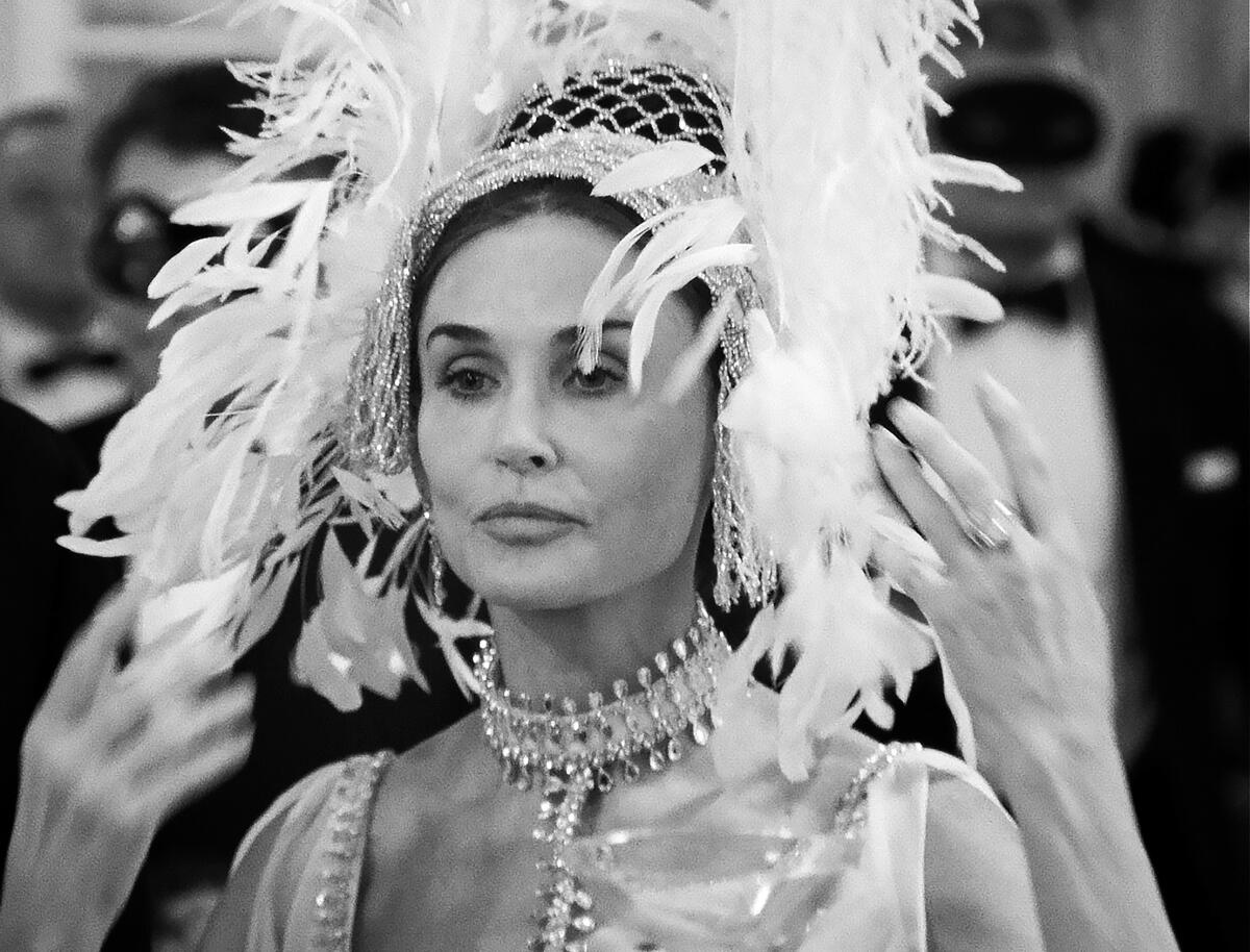 A woman in a large headdress and jewels in a scene from "Feud."